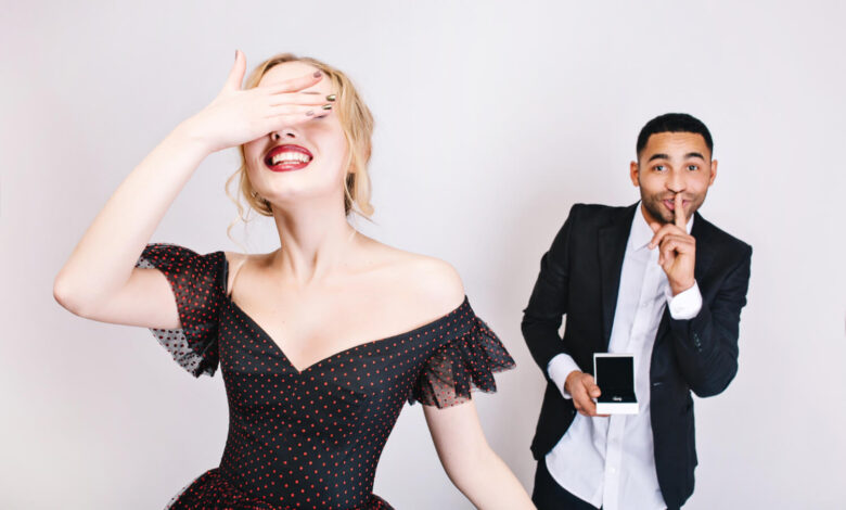 Smiling woman hiding her face playfully as a man shows a photo, symbolizing celebrity secrets behind perfect smiles