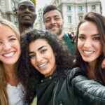Five people smiling together with healthy teeth, illustrating which country has the healthiest teeth.